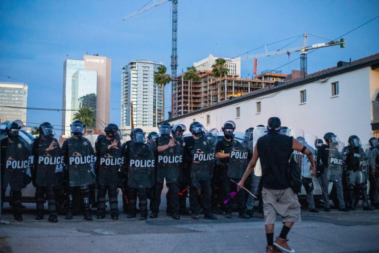 A protester confronts Phoenix police in riot gear just before an 8 p.m. curfew during Black Lives Matter protests in May 2020.