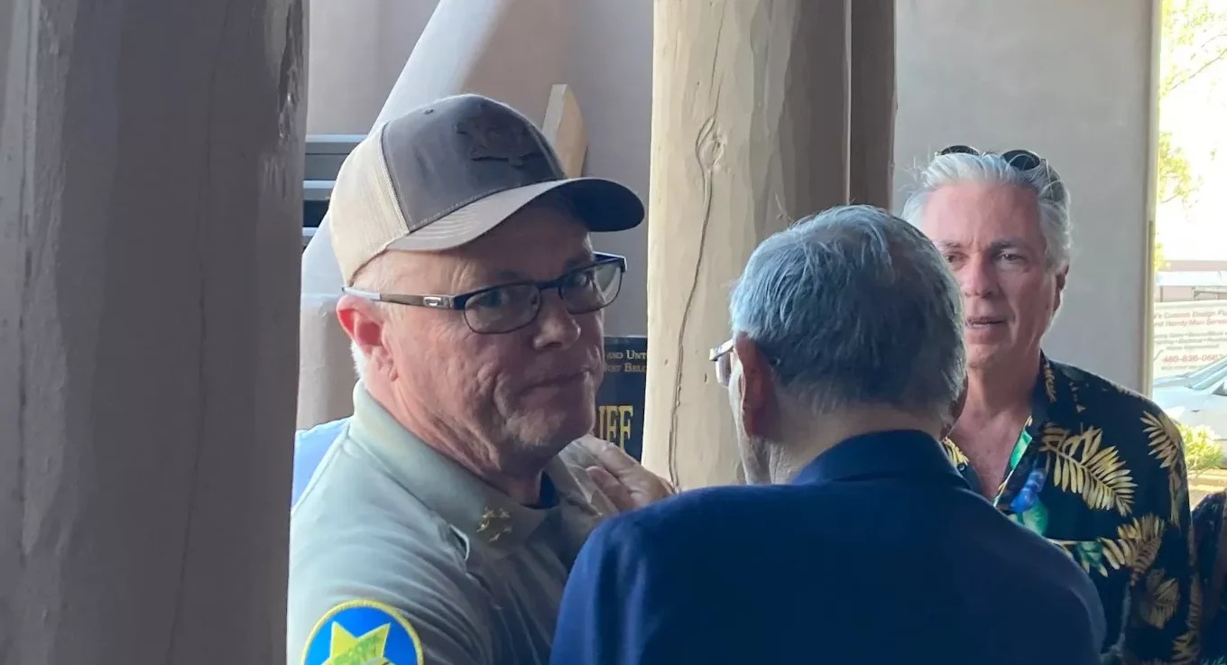 jerry sheridan stares annoyedly at the camera as he hugs joe arpaio