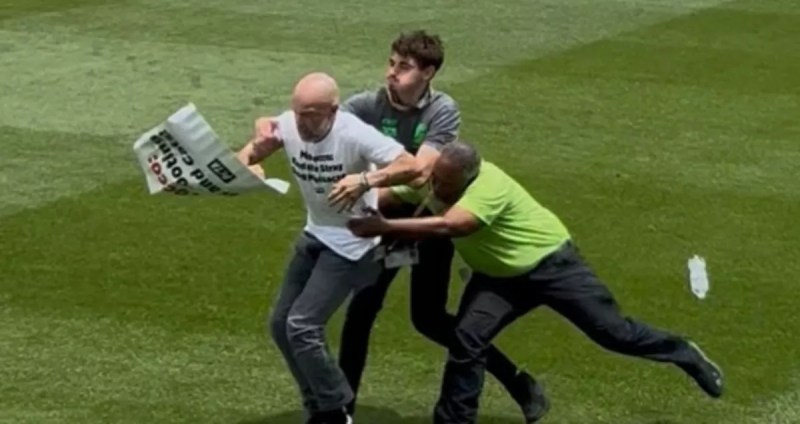 a protester is tackled by two people on a soccer field