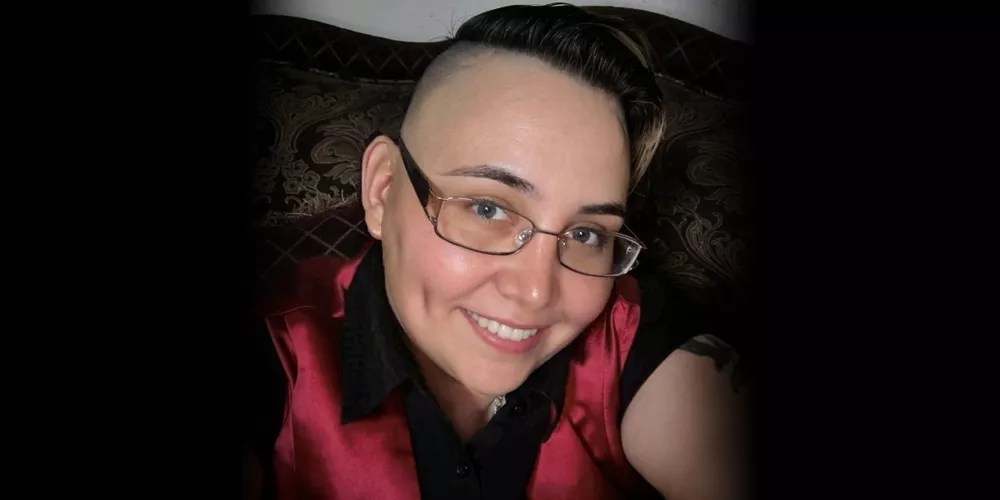 a woman with close-cropped hair and glasses in a selfie