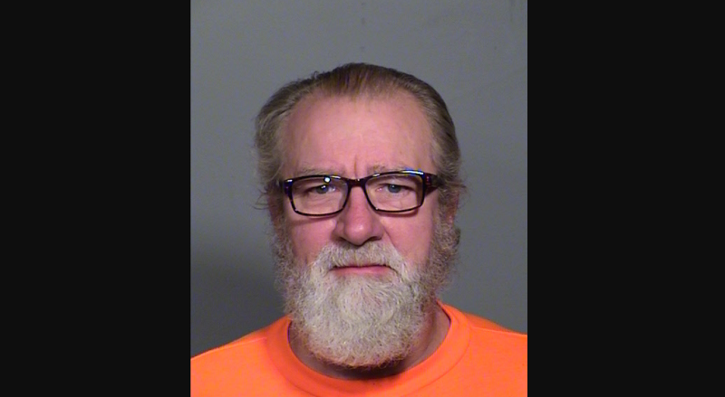 a mugshot of a bearded man in glasses