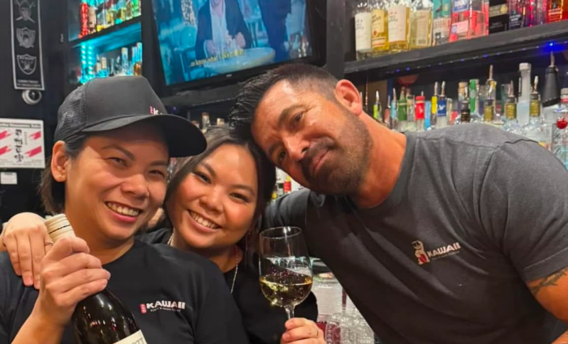 a man and two women pose for a photo in a restaurant
