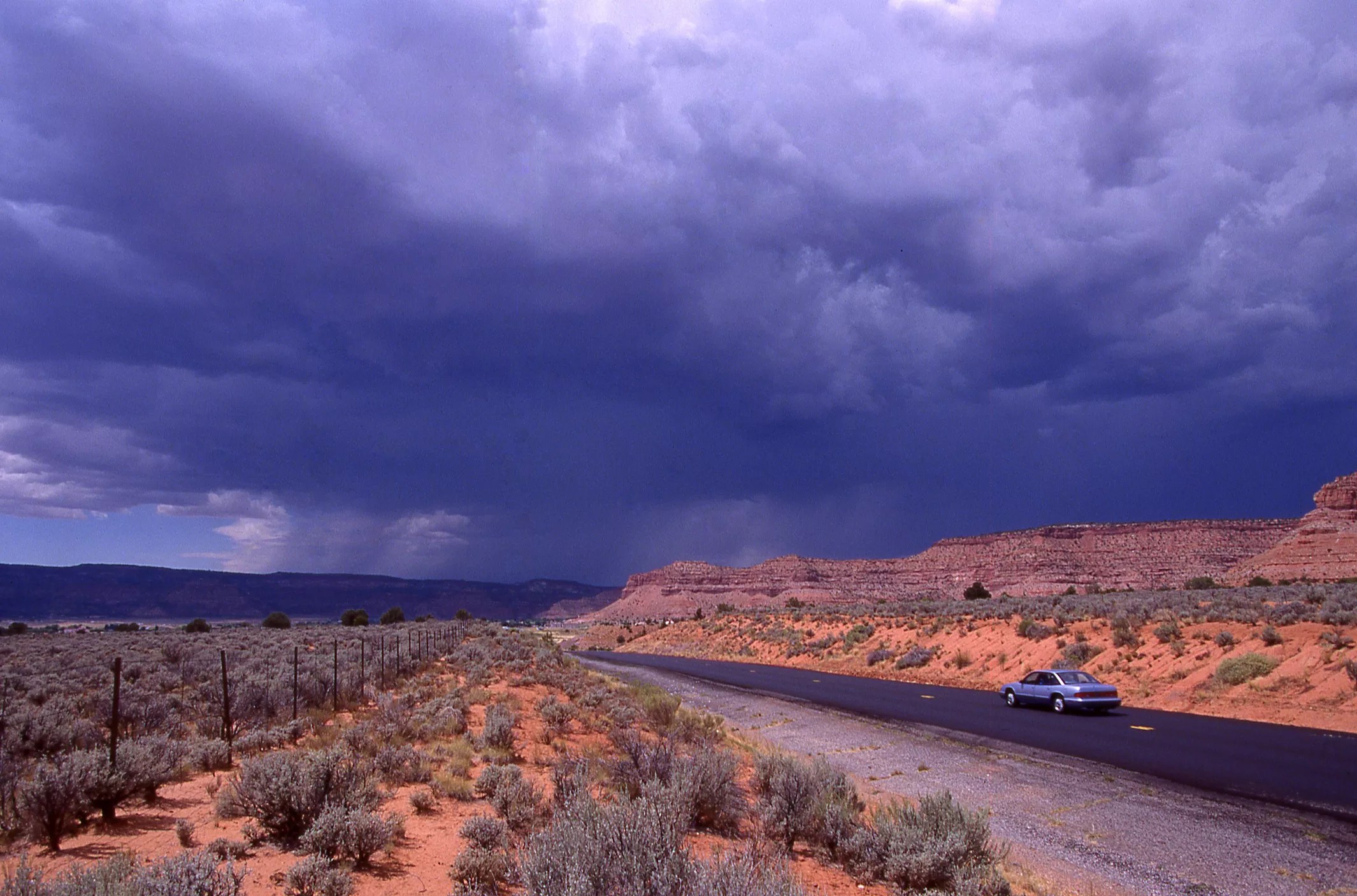 a rural southwestern road with gray clouds above