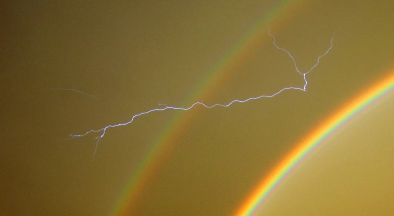 a lightning bolt streaks across a rainbow