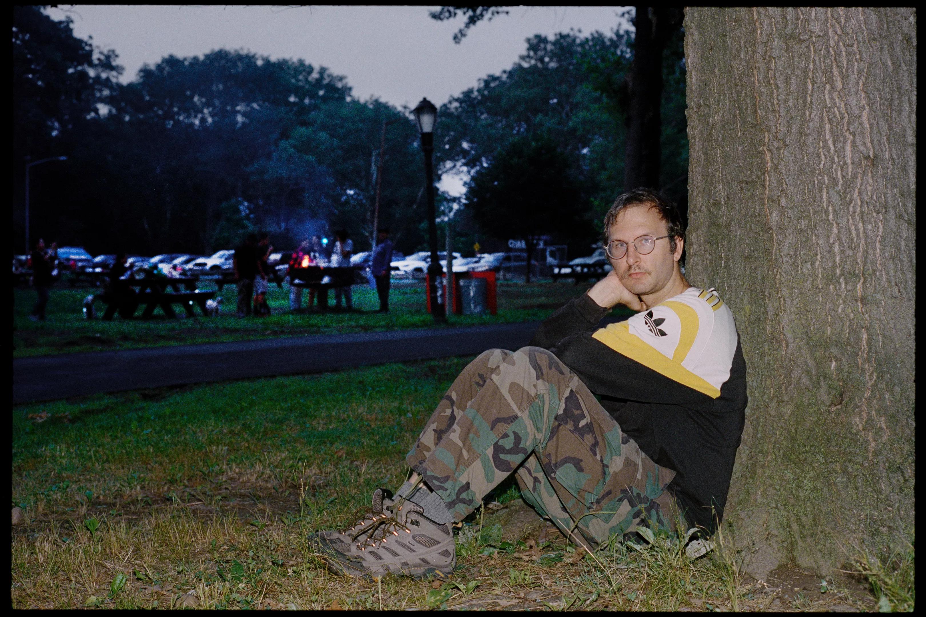 man sits by tree