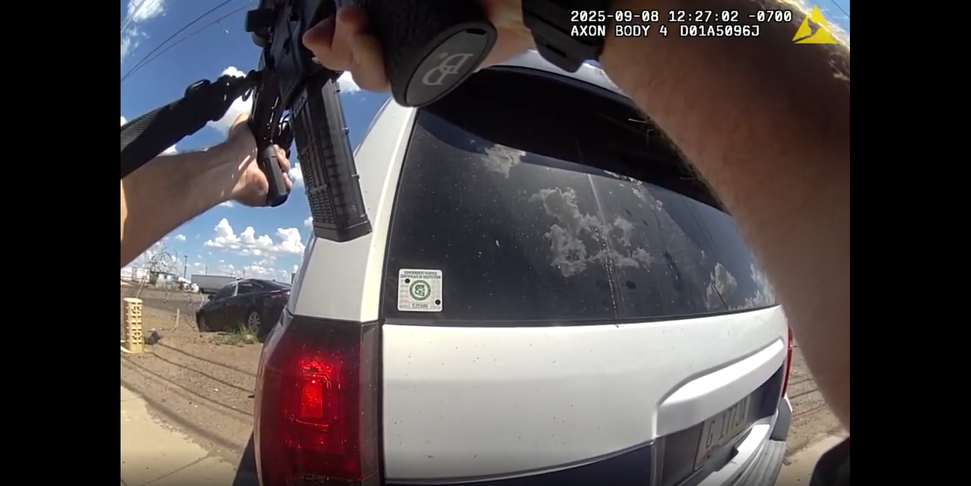 body-camera footage of a person pointing a rifle at a black sedan